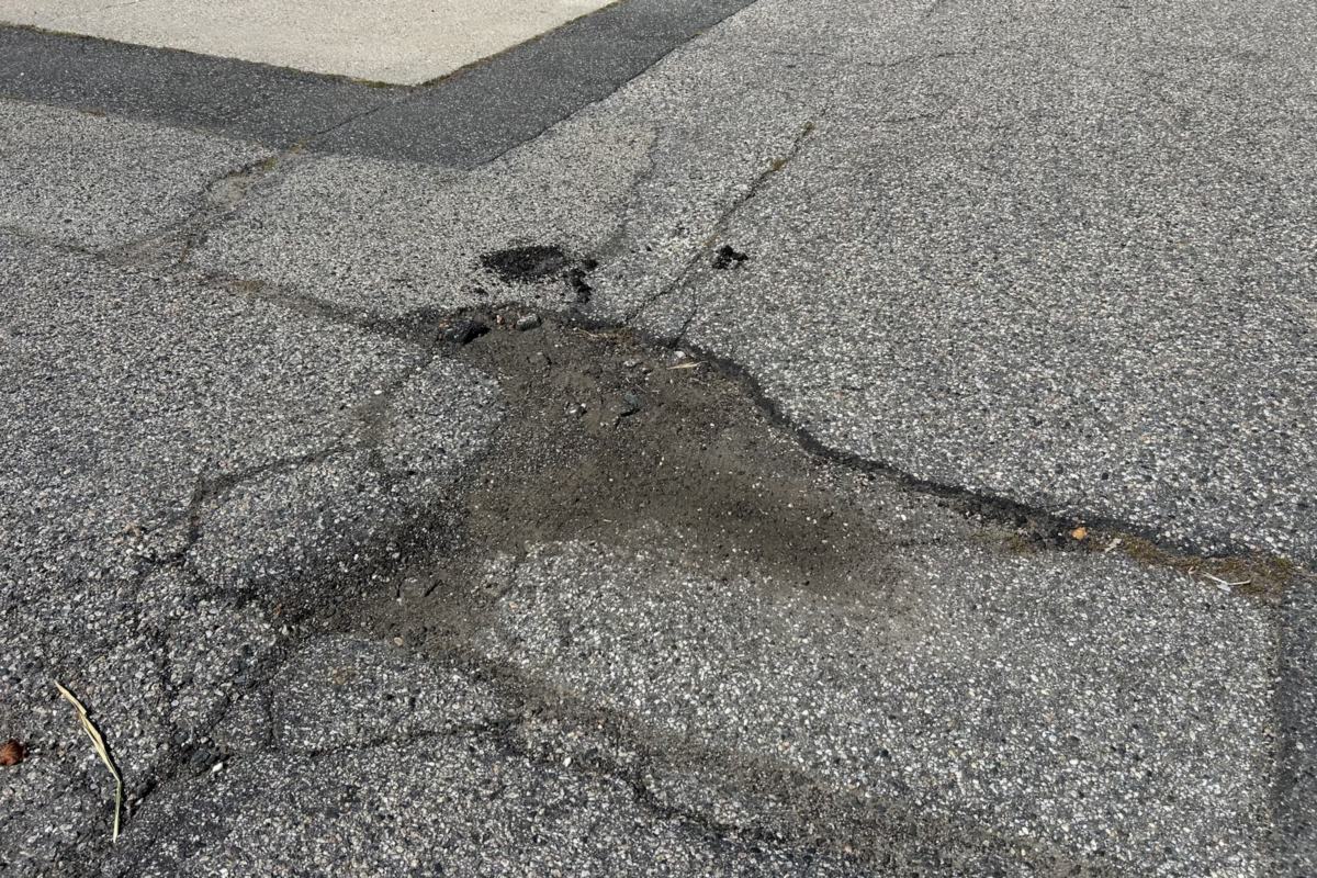 Crumbling, cracked asphalt with the gravel base showing through, the kind of damage Zilembo's repairs
