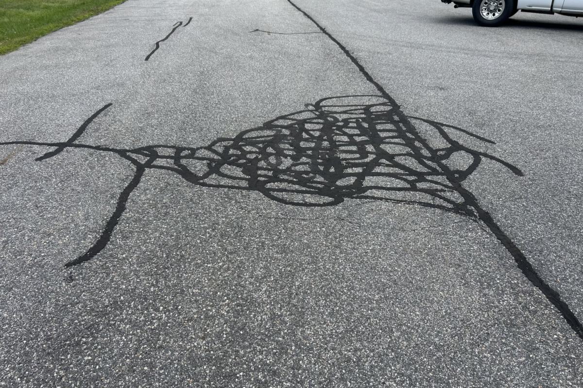 Hot-pour crack sealant filling a network of cracks in an asphalt lot in Southern Maine