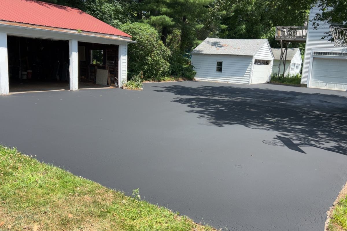 Freshly sealcoated residential driveway with a deep black finish in Southern Maine